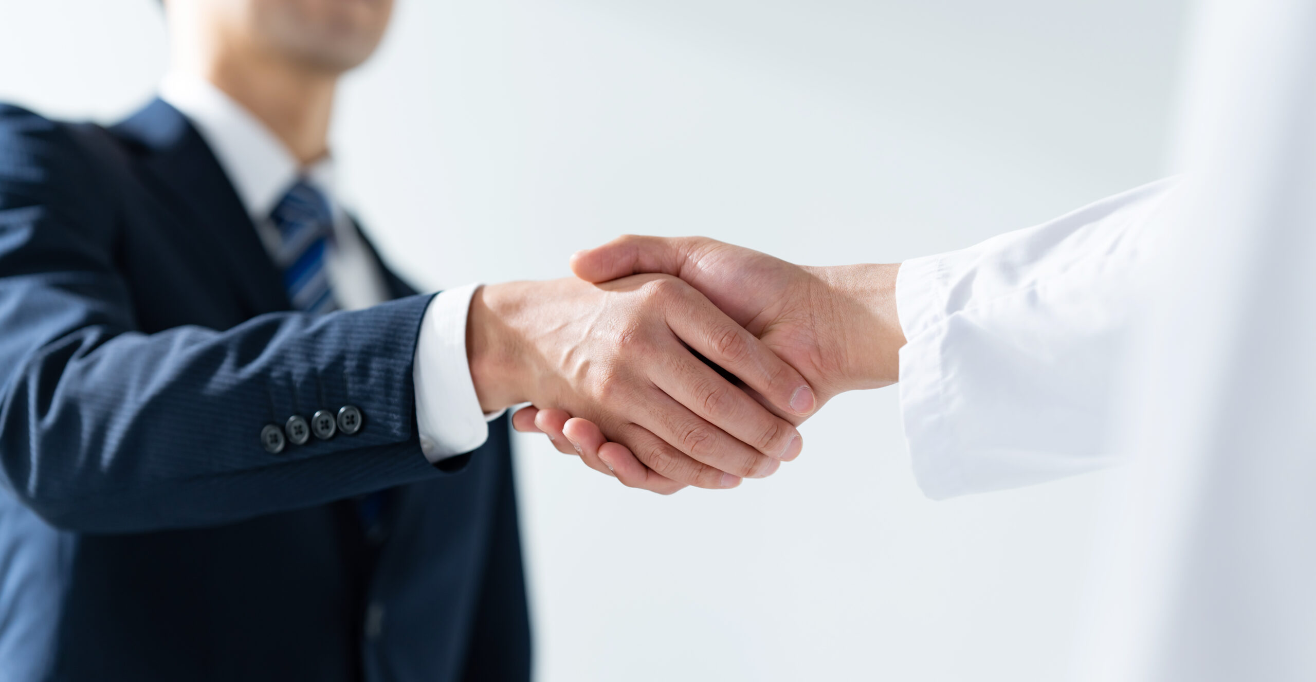 企業担当者と医師が握手する様子